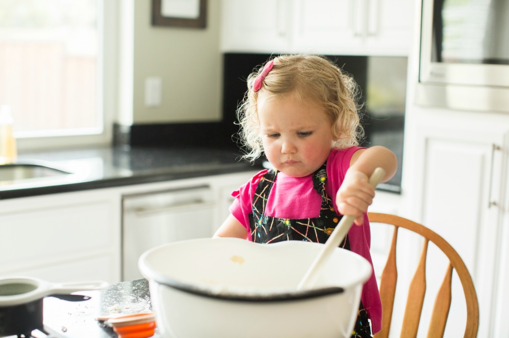 Toddler with large mixing bowl and spoon for cooking activity from Virtual Book Club Summer Camp
