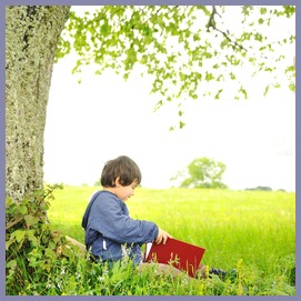 Happy children reading the book under the tree